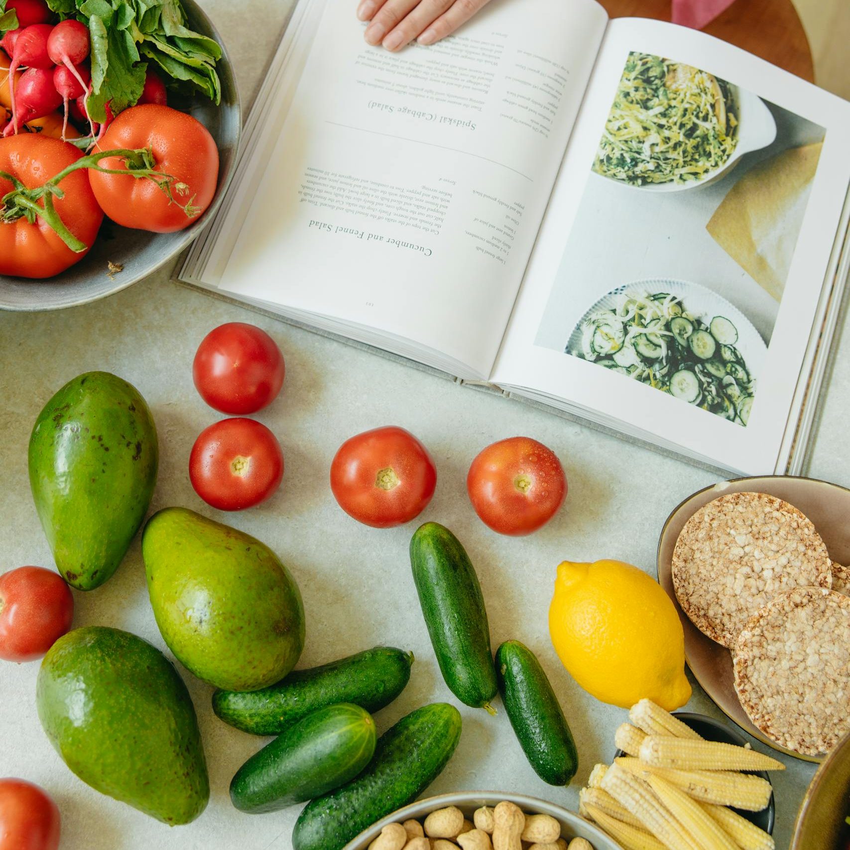 Draufsicht auf frisches Gemüse und ein geöffnetes Kochbuch auf einer Küchenarbeitsplatte, als Teil einer gesunden Ernährung zur Unterstützung des Darms.